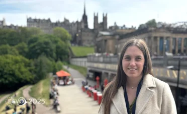 Primer plano de la Dra. María Simó sonriendo al aire libre con vistas panorámicas de Edimburgo al fondo y el logo del ECVO 2025 en la esquina
