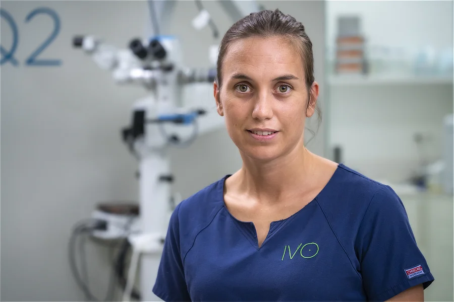 Retrato de la Dra. María Simó en la zona quirúrgica de IVO Barcelona, con equipamiento oftalmológico de fondo.