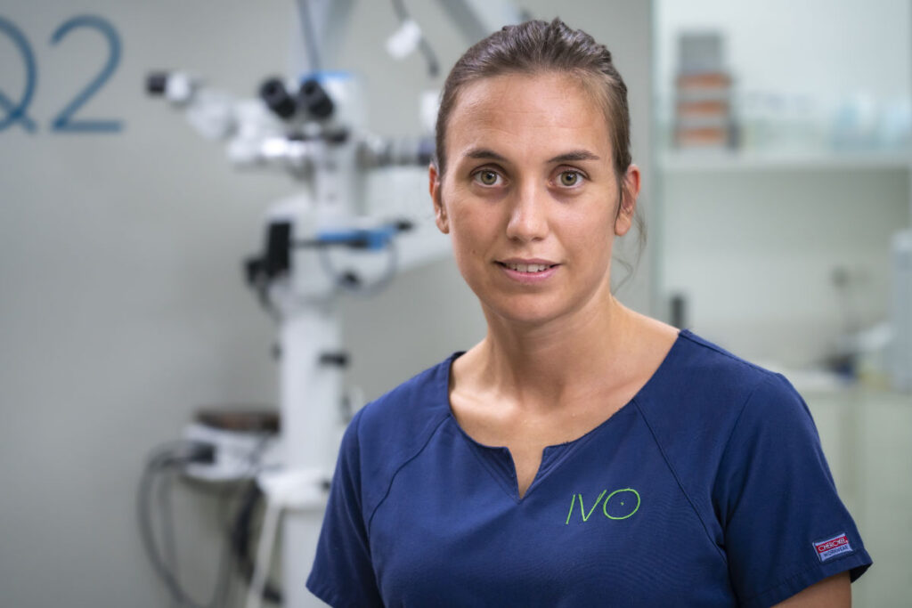 Retrato de la Dra. María Simó, veterinaria oftalmóloga, con uniforme clínico azul en la zona quirúrgica de IVO.